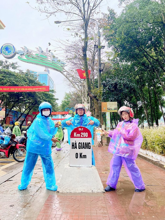 Du khách tranh thủ chụp ảnh tại km số 0 Hà Giang dù trời mưa