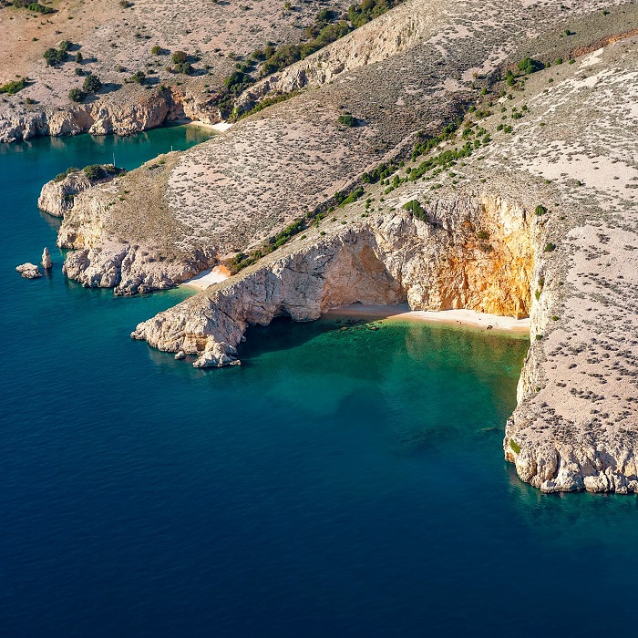 Bãi biển đầy sỏi đá trên một phần của đảo du lịch đảo KRK Croatia